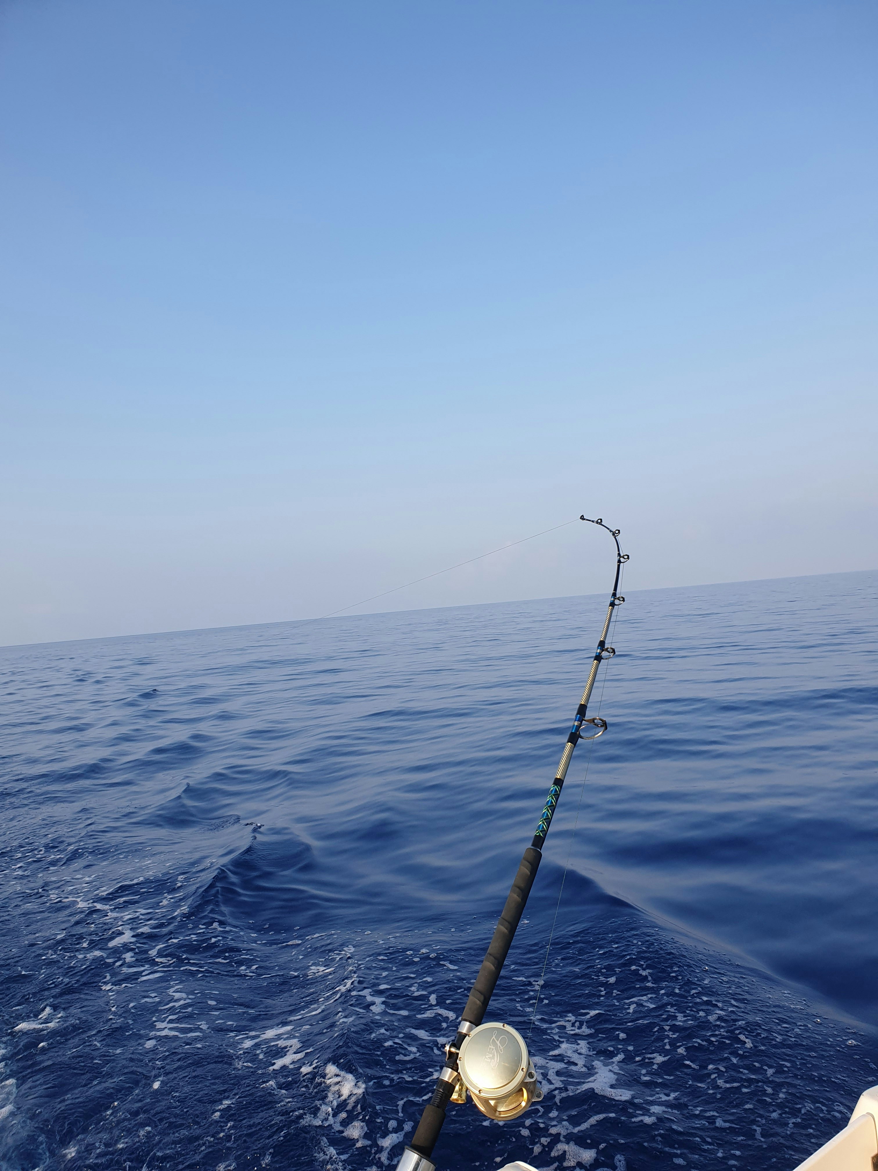 Trolling rod and reel bent over deep blue offshore water