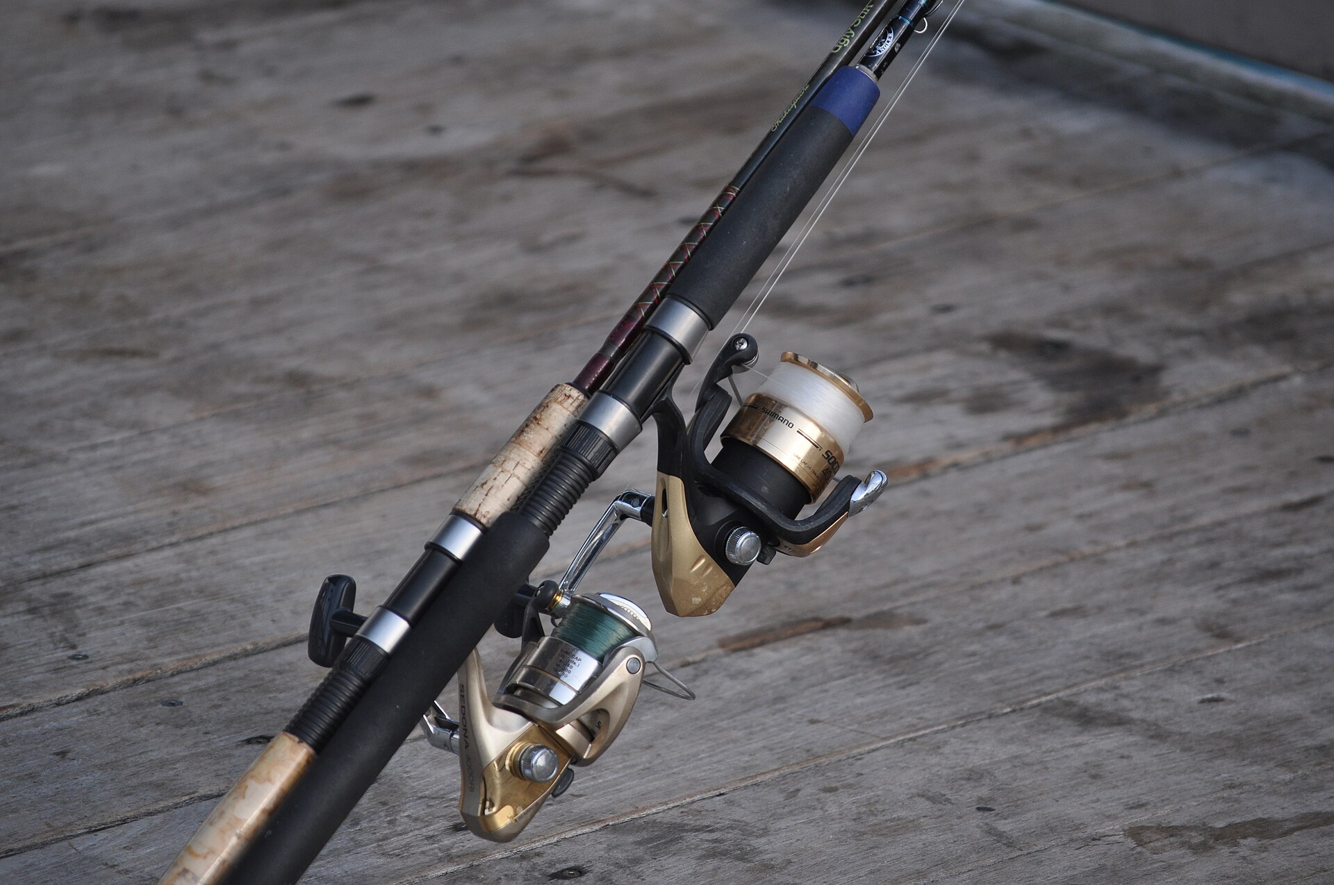 Two spinning rods and reels set up on a fishing pier