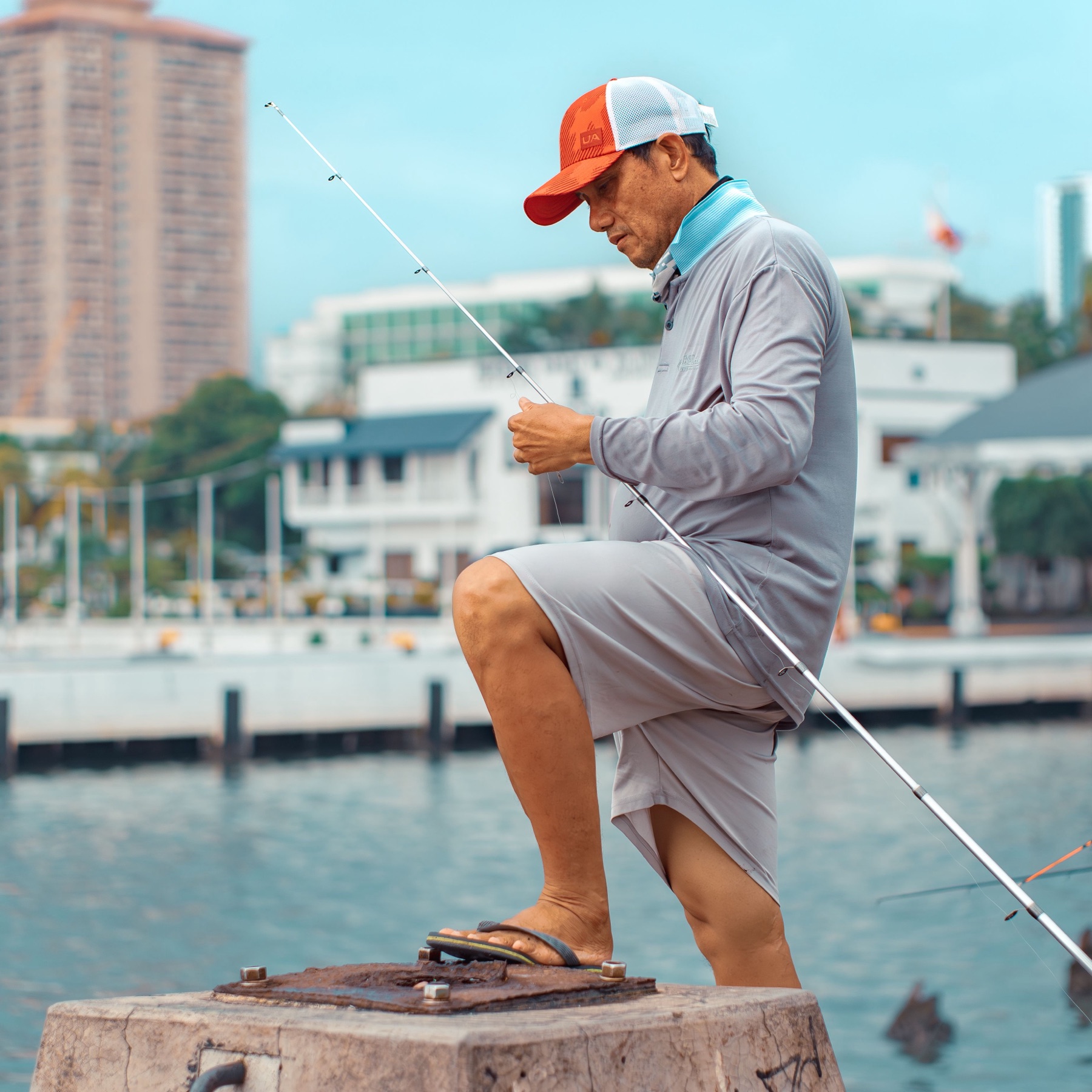 Angler in a long-sleeve sun shirt and trucker cap rigging a rod on the water