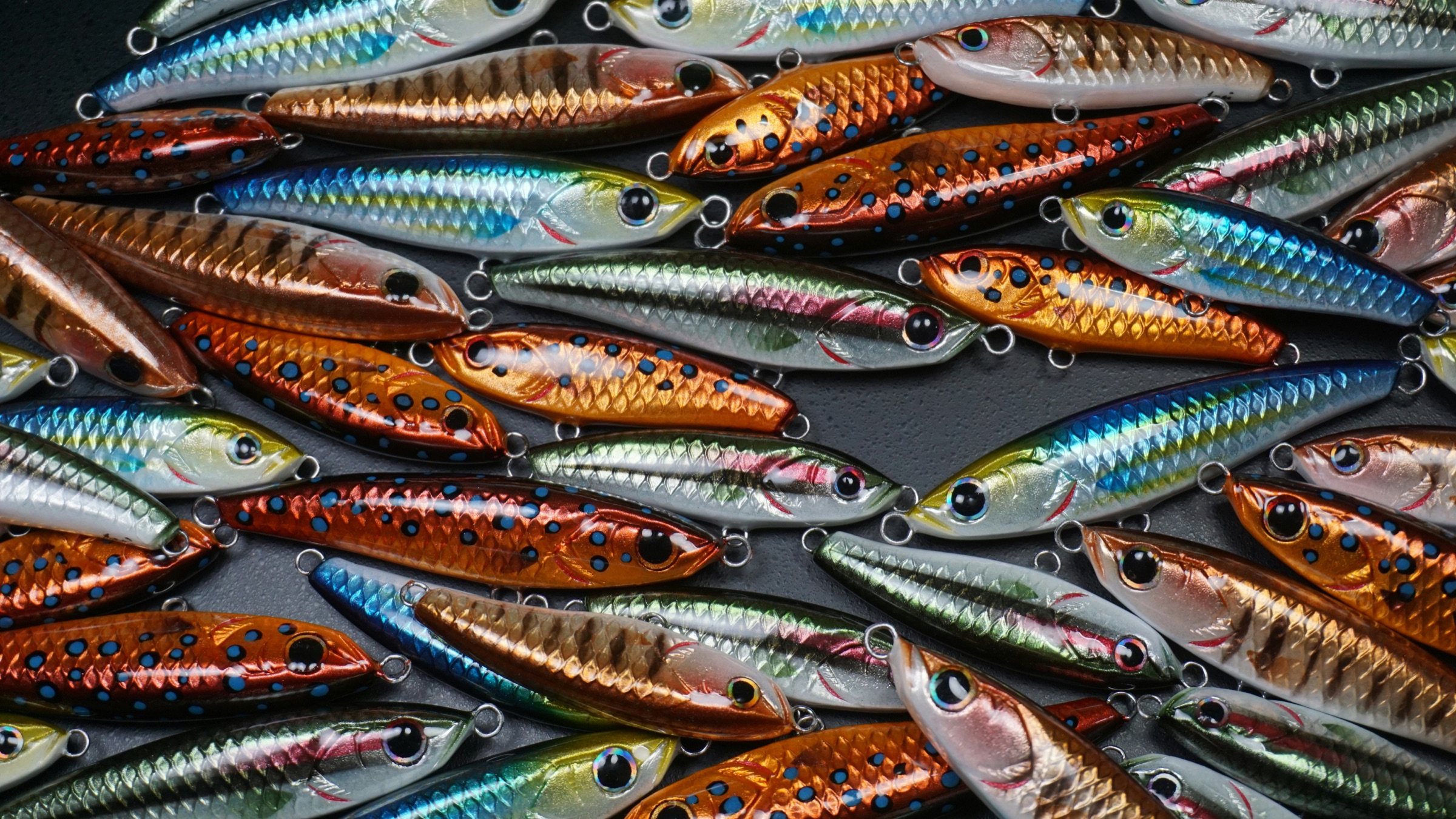 Rows of saltwater jerkbait lures in silver, blue, and orange finishes